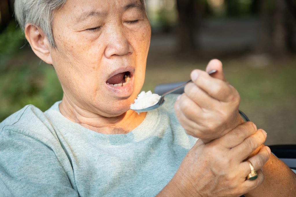 Woman with parkinsons holding a spoon with tremors